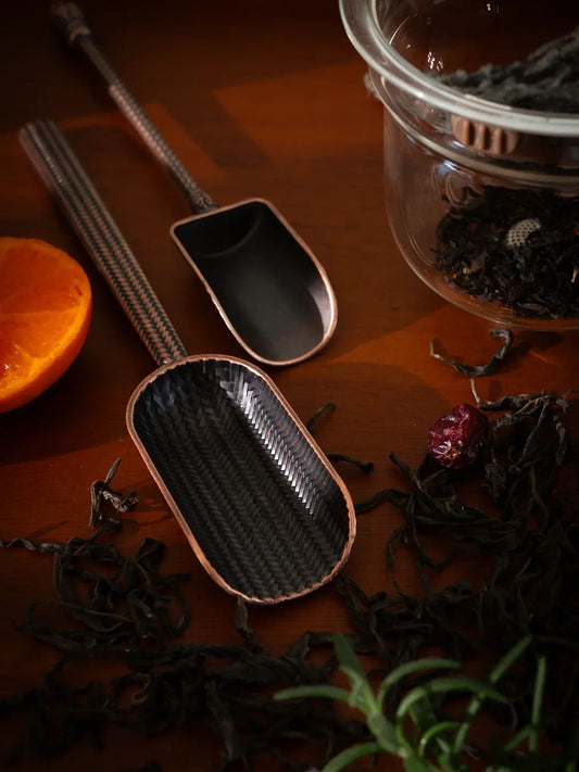 Vintage Spoon with a woven texture scoop, placed on a wooden surface with tea leaves.