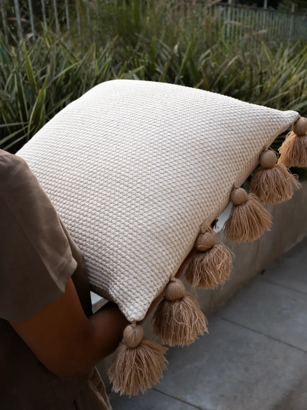 Waffle cushion cover with tassels, cotton linen boho pillow held outdoors