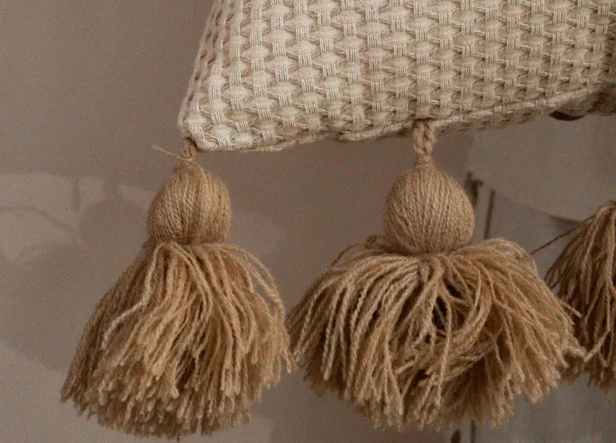 Close-up of hand-tied tassels on waffle cushion cover with textured weave