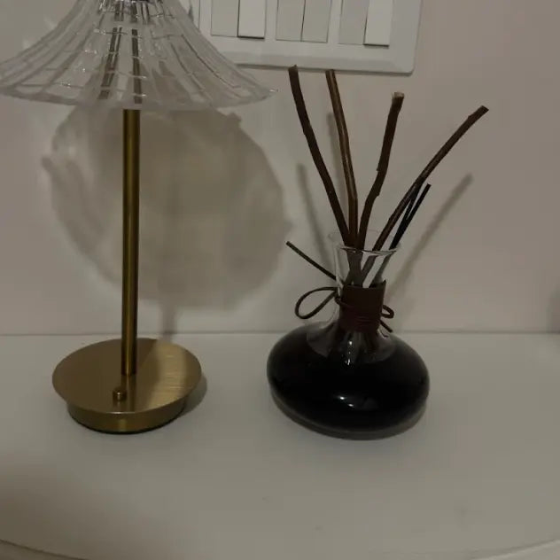 Wine reed diffuser and a decorative lamp on a white surface with a neutral background