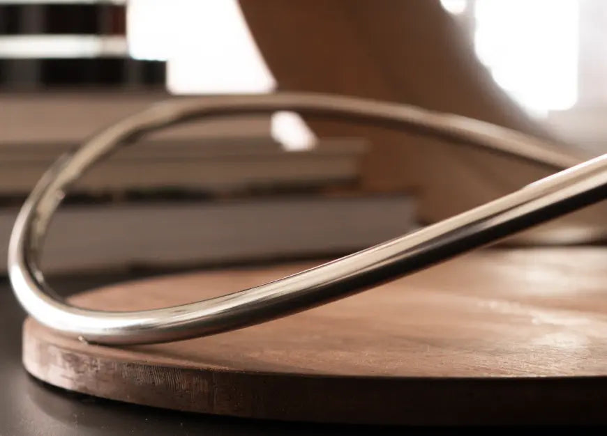 Close-up of stainless steel arc handle on modern wooden tray