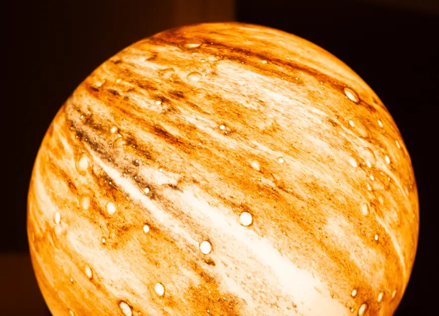 Close-up of Cosmo glass table lamp shade glowing with warm ambient light