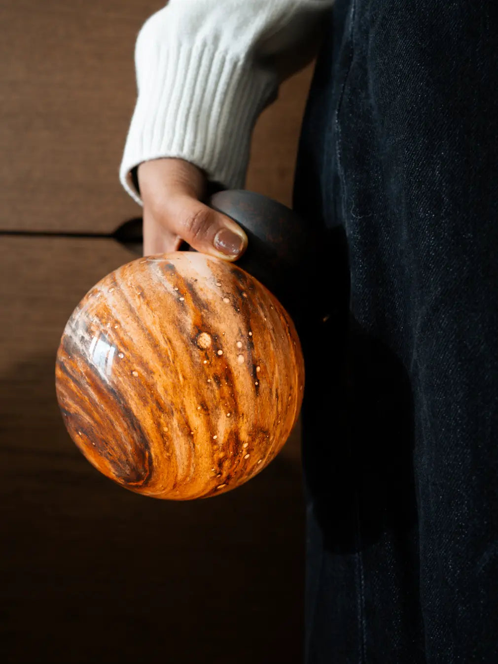 Cosmo rechargeable table lamp held by hand showing its compact cordless design