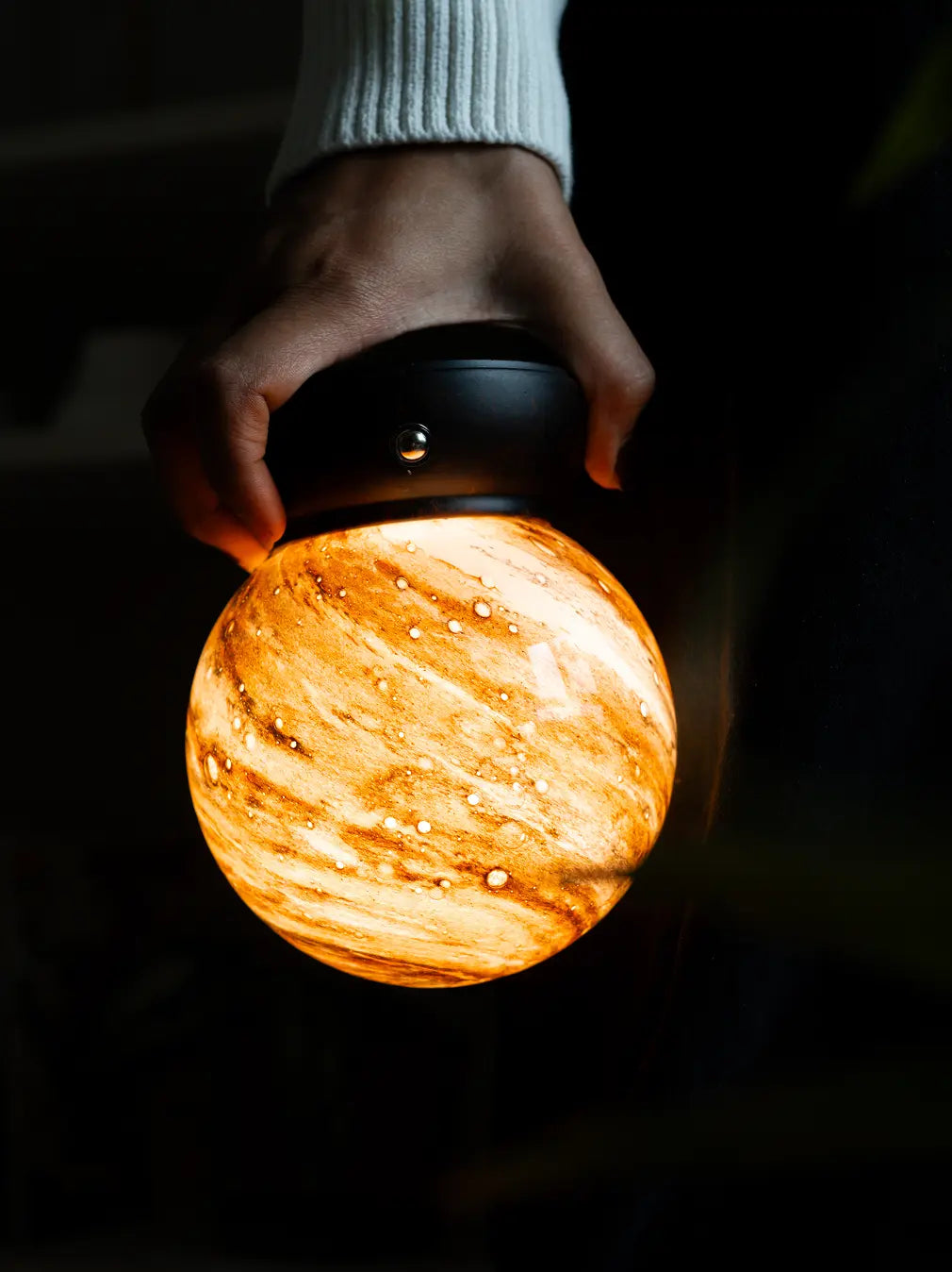 Cosmo rechargeable glass lamp glowing with warm ambient light in a dark setting