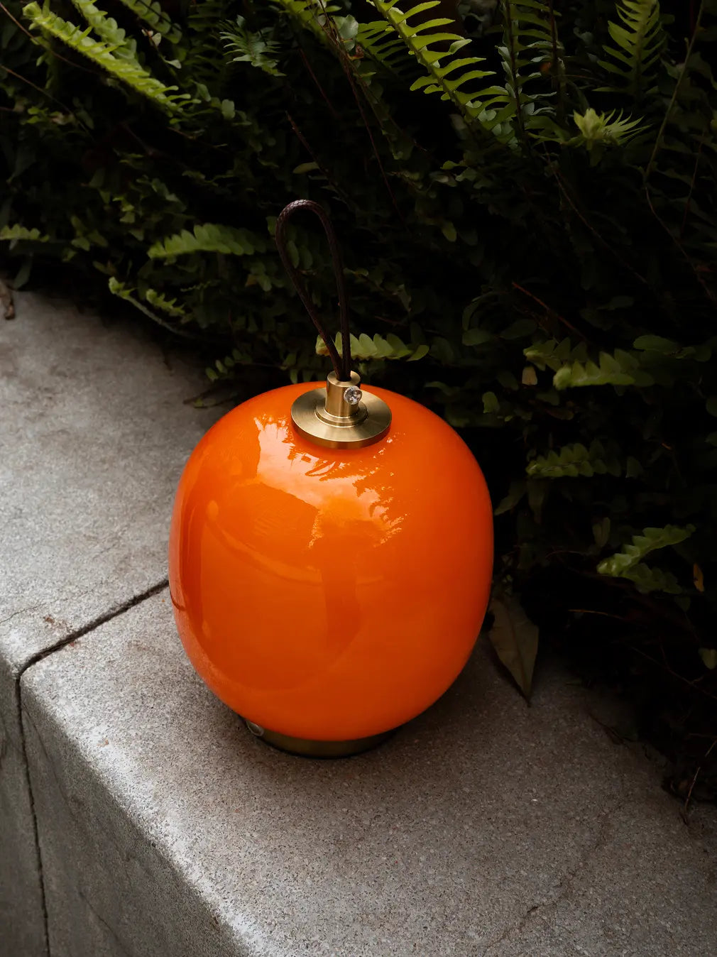 Orange Dew cordless glass table lamp with leather handle styled outdoors