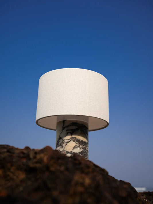 Fossil Italian marble table lamp with a white fabric shade against a blue sky