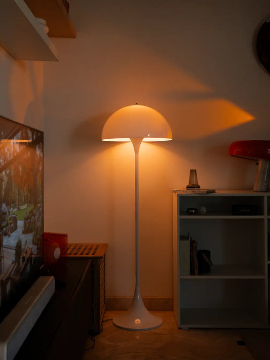 Nova white floor lamp casting a warm glow in a living room corner