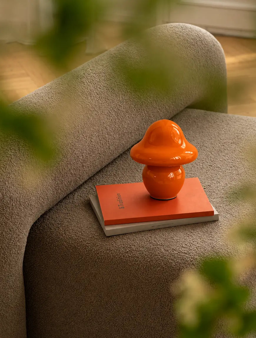 Mini orange mushroom table lamp styled on books beside a modern sofa