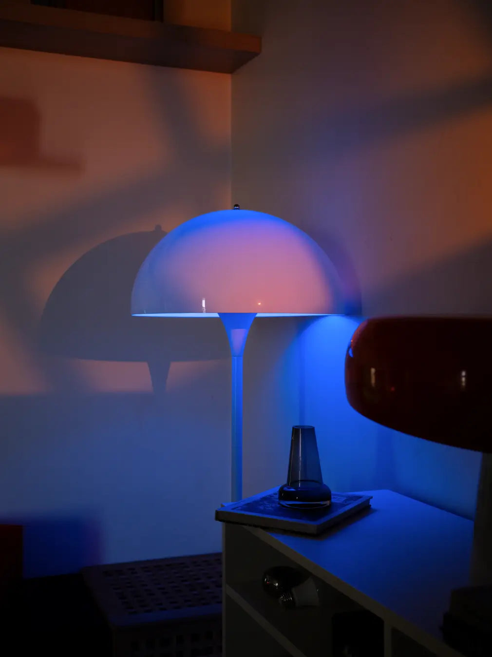 Nova white floor lamp casting blue accent light beside a cabinet