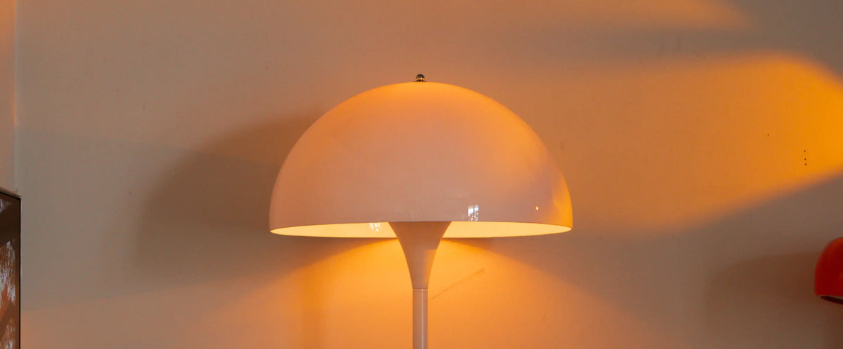 Nova white floor lamp dome close-up casting warm golden light across the wall
