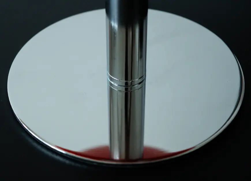 Close-up of the Orbit table lamp’s reflective chrome base and slender metal stem.