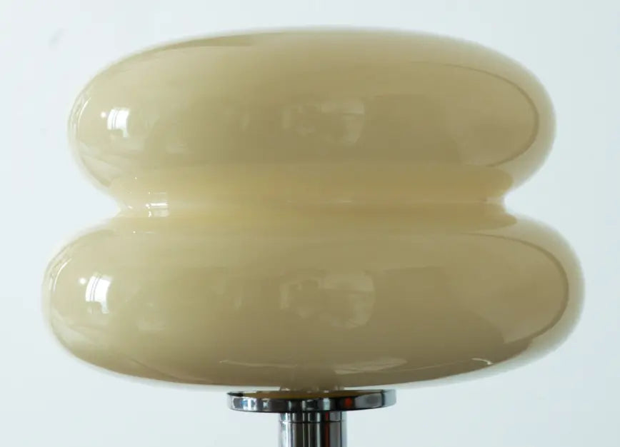 Close-up of the Orbit table lamp’s glossy yellow glass shade with a cinched profile.