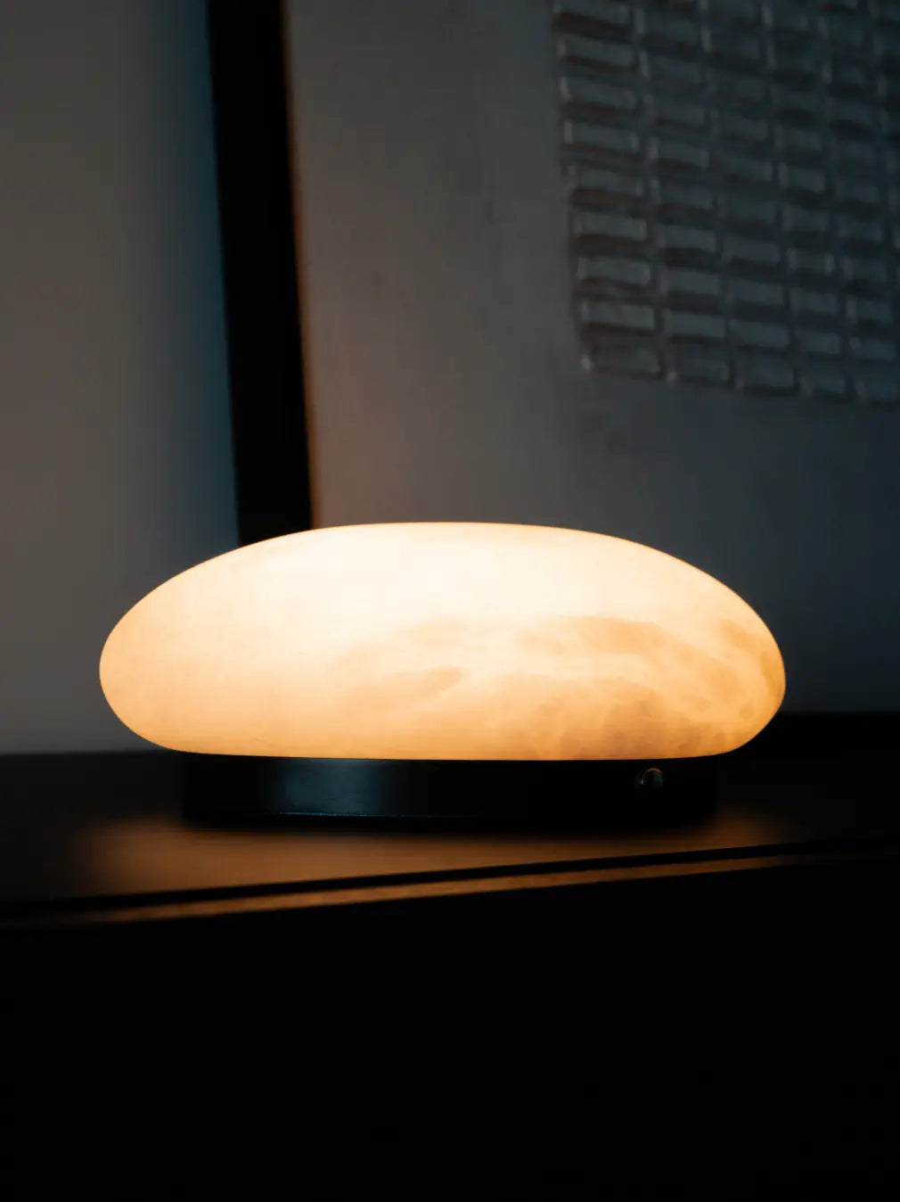 Close-up of Pebble Marble Portable Table Lamp with glowing marble shade and black base